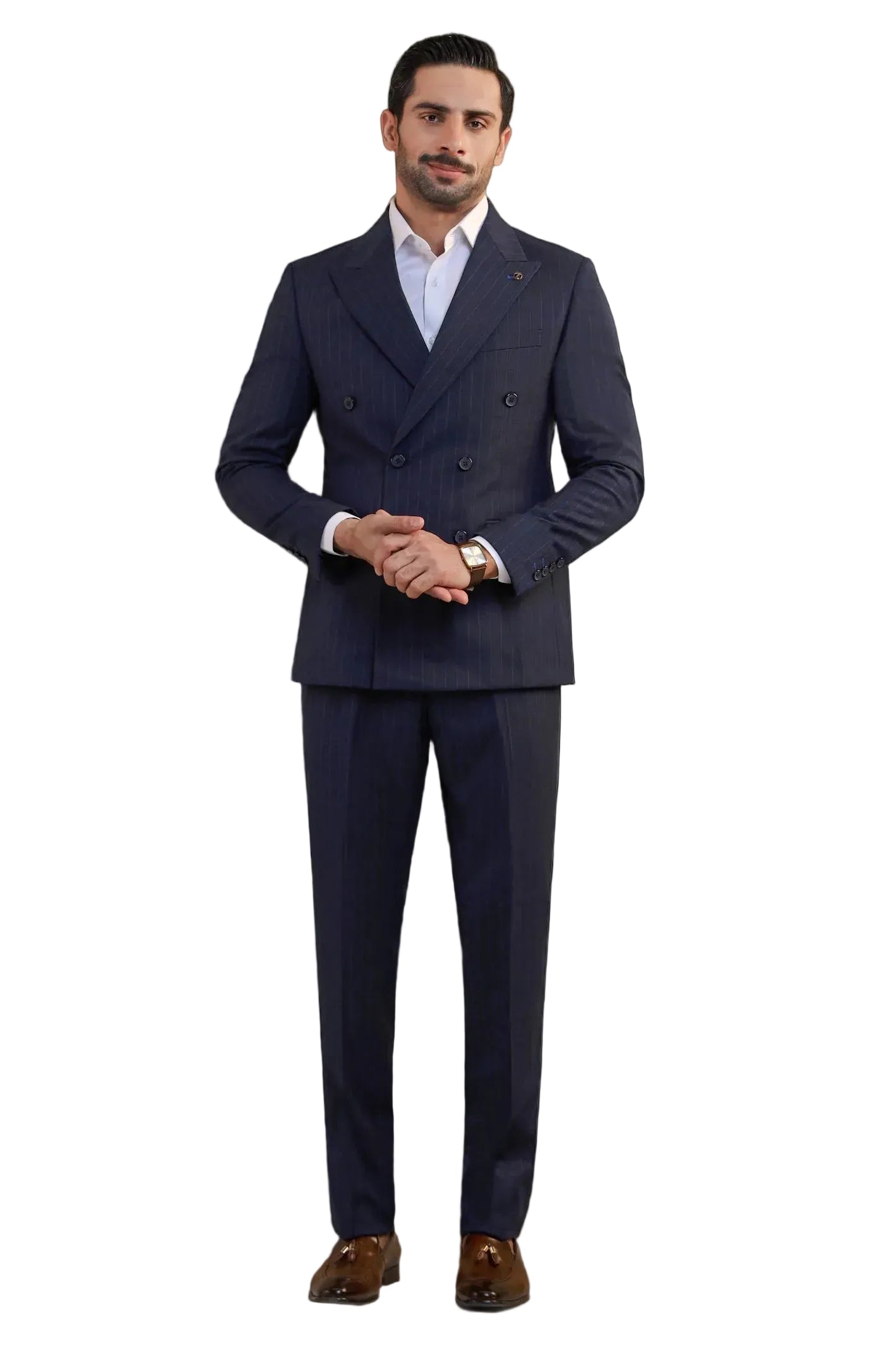 A man modeling a dark navy blue double-breasted pinstripe suit with a white dress shirt and brown leather dress shoes, standing against a light gray studio background.