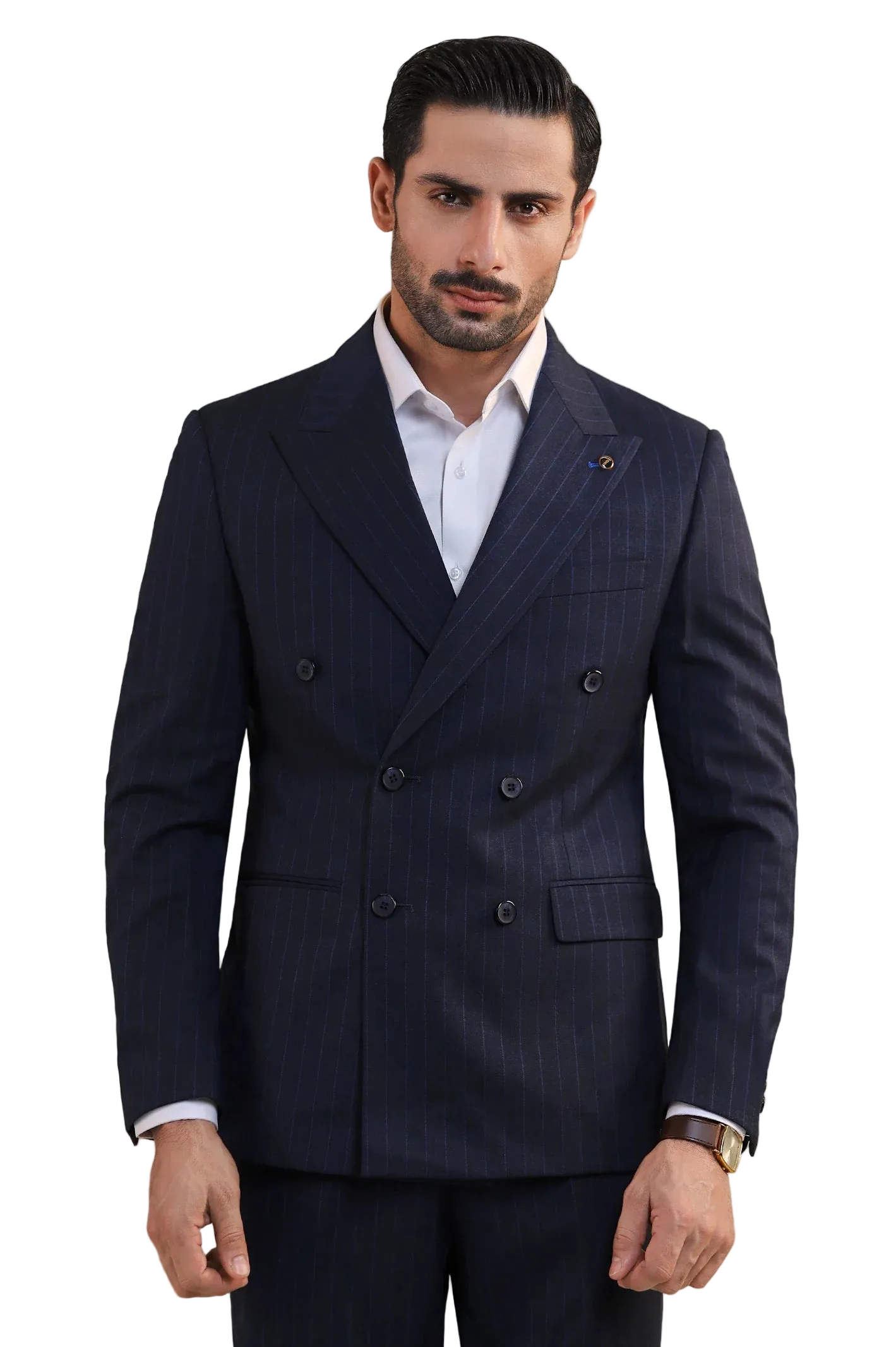 A man wearing a dark navy blue double-breasted pinstripe suit jacket over a white dress shirt, standing against a light gray studio background.